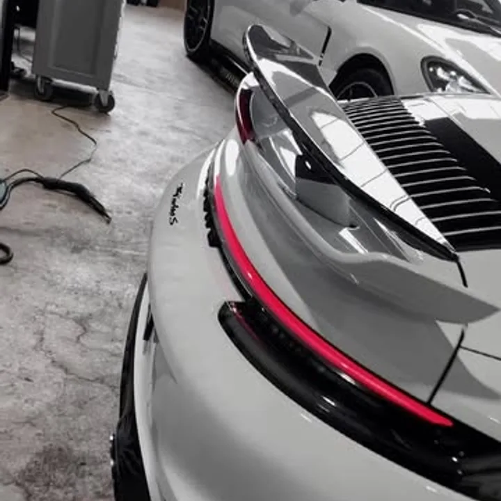 Heck eines weißen Porsche 911 Turbo S mit Heckflügel in der Werkstatt von Edelfoliert